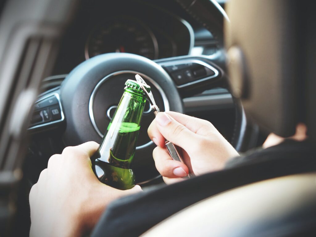 Misdemeanors that prevent employment: A man behind the wheels opening a bottle of beer.